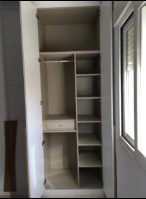 Interior de armario a medida con fondo reducido, barra, baldas y cajón adaptado junto a una puerta