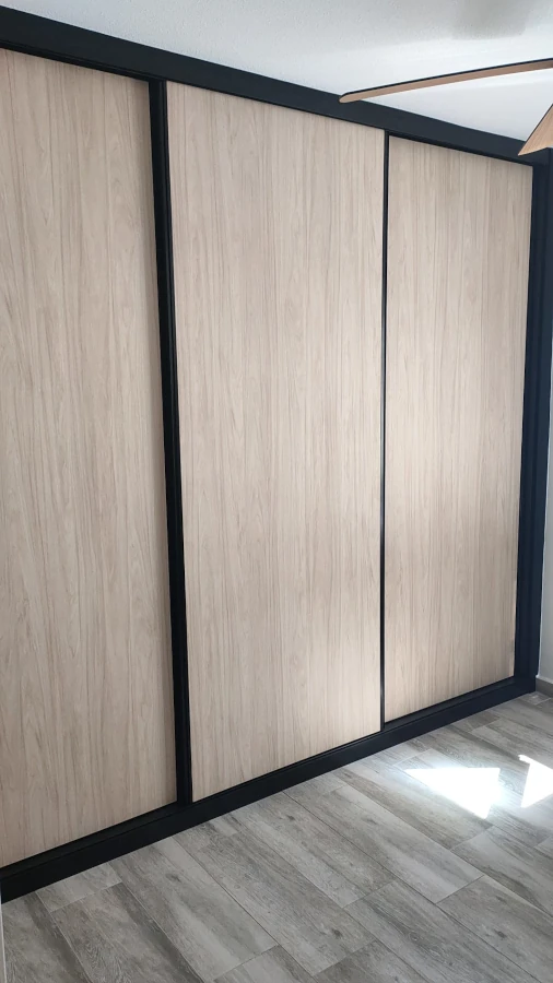 Armario empotrado a medida con puertas correderas en Hickory Frida y detalles negros en Sevilla